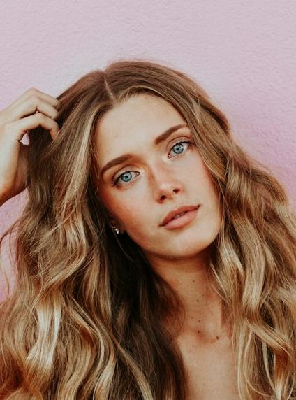 woman standing next to pink wall while scratching her head